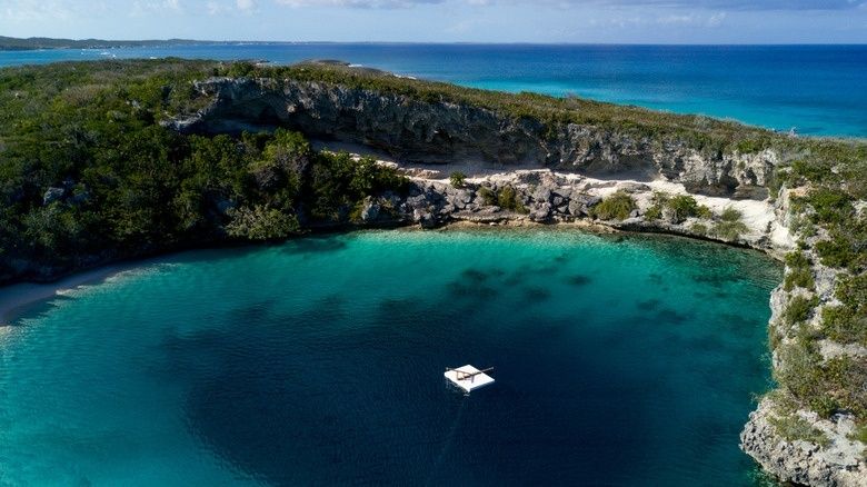 Aerial view of a turquoise Bahamian blue hole beside the sea